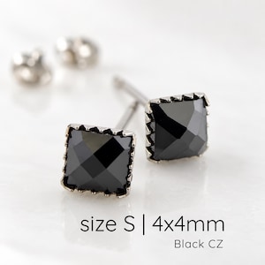 Puede incluir: Un par de pendientes de bot&oacute;n cuadrados con piedras de circonita c&uacute;bica negra facetadas en un marco met&aacute;lico. El texto size S | 4x4mm Black CZ es visible. Cada pendiente tiene un poste y un cierre met&aacute;lico a juego incluido.