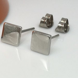 May include: A pair of silver square stud earrings with a brushed finish. The earrings have a post and butterfly backing.