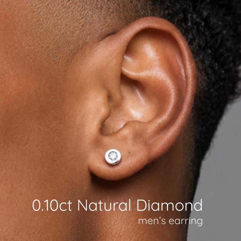 May include: A silver-toned stud earring featuring a round, bezel-set 0.10ct natural diamond. The text 0.10ct Natural Diamond is printed in white at the bottom of the image, along with the text men's earring below it.