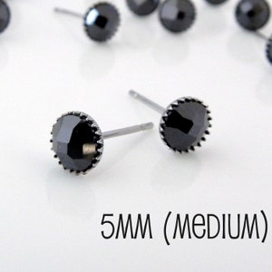 May include: A pair of black stud earrings with a 5mm round black stone set in a silver bezel. The earrings are 5mm (medium) in size.