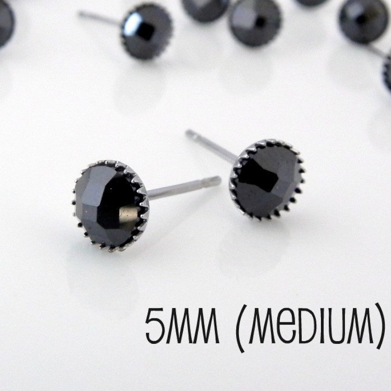 May include: A pair of black stud earrings with a 5mm round black stone set in a silver bezel. The earrings are 5mm (medium) in size.