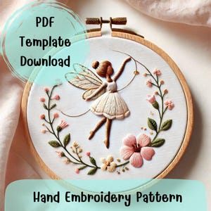 May include: A PDF template download for a hand embroidery pattern featuring a fairy with wings and a floral wreath. The fairy is holding a string of beads and is wearing a white dress. The wreath is made of green leaves and pink flowers.