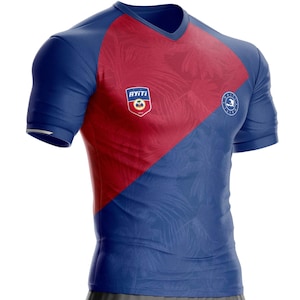 Peut inclure: Un maillot de sport bleu et rouge à manches courtes et col en V. Le maillot présente un motif bicolore en diagonale, avec une section rouge en haut à gauche et une section bleue en bas à droite. Le maillot comporte deux écussons.