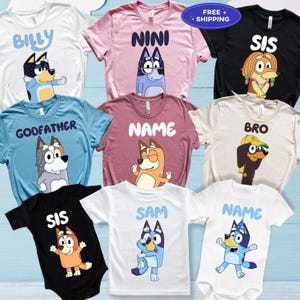 May include: A collection of t-shirts and onesies featuring cartoon dog characters. The shirts are in various colors, including white, pink, blue, and black, with names like "Billy," "Nini," and "Sis" printed on them. The designs are colorful and playful.