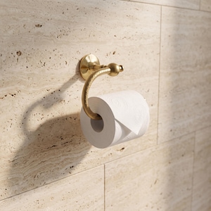 May include: A wall-mounted toilet roll holder with a brushed gold finish and a curved, textured arm. The holder features a circular base plate and a rounded finial at the end of the arm, currently holding a roll of white toilet paper.