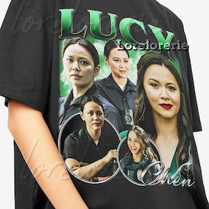 May include: Black t-shirt featuring a graphic of a woman with the name "Lucy Chen" in green block letters. The design includes multiple images of the woman in various poses, with a green background.