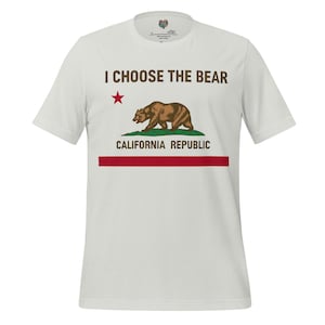 Peut inclure: T-shirt blanc avec le drapeau de la République de Californie. Le motif comprend un ours brun, une étoile rouge et le texte "I Choose The Bear" et "California Republic" en marron et rouge.