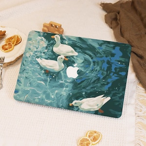 May include: A laptop skin with a design of three white ducks swimming in a blue and green water pattern.