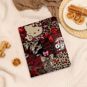 May include: A decorative notebook with a collage design featuring a Hello Kitty illustration, leopard print, bows, cherries, and the text "Fuck". The color palette includes red, brown, and pink.