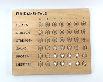 May include: Wooden "Fundamentals" checklist with the text "UP AT 5", "STRETCH", "STRENGTH", "SALAD", "PROTEIN", and "MEDITATE". Each activity has a series of hexagonal spaces for tracking progress. The board is light brown.