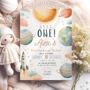 Puede incluir: Una invitación caprichosa para una celebración de primer cumpleaños. El diseño presenta una ilustración en acuarela de planetas, el sol y un cohete. El texto dice "ONE! Alex's First Trip Around The Sun!" con detalles del evento.