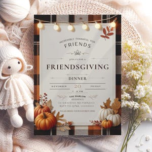 Op de afbeelding: Een Friendsgiving-uitnodiging met een geruite rand, pompoenen en herfstbladeren. De tekst luidt "Ongelooflijk dankbaar voor vrienden" en details voor een diner op 20 november. Decoratieve lichtslingers en een bloemstuk maken het ontwerp compleet.