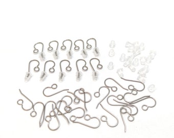 May include: A set of silver earring hooks and clear earring backs. There are 12 earring hooks and 20 earring backs.