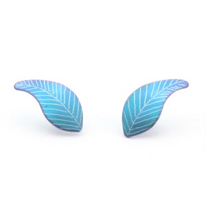 May include: A pair of blue leaf-shaped earrings with white lines etched into the surface. The earrings have a subtle iridescent finish.