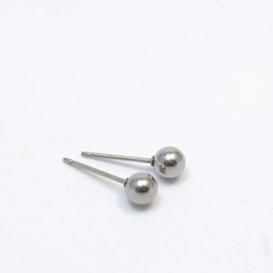 Könnte beinhalten: Ein Paar silberne Ohrstecker mit Kugeln. Die Ohrringe sind schlicht und elegant und eignen sich hervorragend als Geschenk für jeden Anlass.
