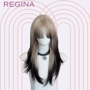 Puede incluir: Peluca bicolor con la parte superior rubia clara y la inferior marrón oscuro, peinada con flequillo. La peluca se muestra en una cabeza de maniquí, combinada con un collar de gargantilla negro. La palabra "REGINA" es visible en la parte superior.