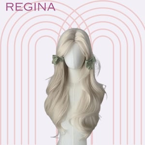 May include: A long, wavy, light blonde wig with a centre parting. The wig is styled with two green hair clips on either side of the head.