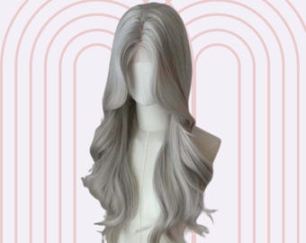 May include: A long, wavy, silver-grey wig with a light blonde highlight. The wig is styled with loose waves and a center part.