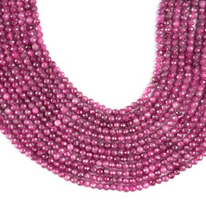 May include: A strand of pink faceted gemstone beads. The beads are round and have a smooth, polished finish.