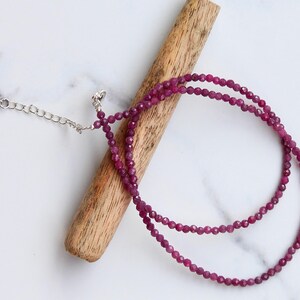 May include: A delicate double-strand necklace made with small, faceted, pink gemstone beads. The necklace is made with a silver clasp and chain.