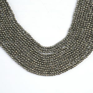 May include: A strand of faceted pyrite beads, each bead is a shimmering metallic gold color.