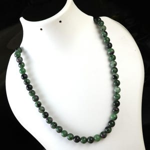 May include: A green and black gemstone bead necklace. The beads are round and have a smooth, polished finish.