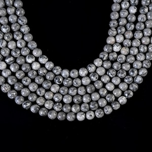 May include: A strand of gray and black marbled round beads. The beads are approximately 8mm in diameter and are strung on a clear elastic cord.