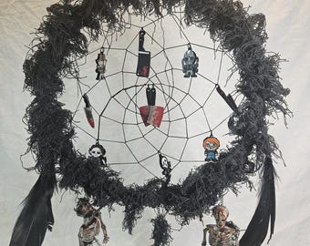 May include: A black Halloween dreamcatcher with a web design, adorned with miniature horror-themed charms, including knives, a skull, and a skeleton. Black feathers hang from the bottom. The dreamcatcher is suspended by a chain.