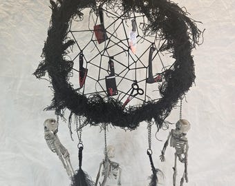 May include: A Halloween-themed dreamcatcher with a black woven frame, adorned with miniature knives and scissors. The dreamcatcher features hanging skeletons and black feathers, creating a spooky decorative piece.
