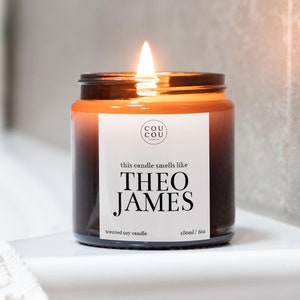May include: A brown glass candle jar with a white label that reads "COU COU" and "this candle smells like THEO JAMES". The candle is scented soy and is 180ml/6oz.