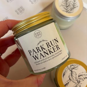 May include: A clear glass jar with a gold lid, labeled "PARK RUN WANKER" with the text "smells like a... infused with of saturday mornings, fresh air and a new personal best." The jar contains a scented soy candle, 4 oz.