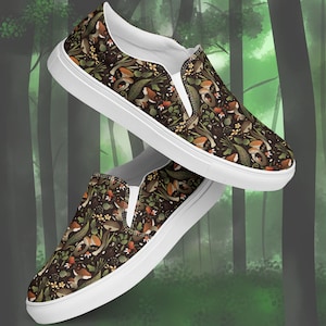 May include: A pair of slip-on canvas shoes with a dark brown background and a repeating pattern of mushrooms, leaves, and small flowers. The shoes have white soles and a white trim around the opening.