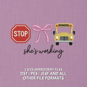 May include: An embroidered design featuring a red stop sign, a pink bow, and a yellow school bus with the word "SCHOOL" on top. The phrase "she's working" is written below the bow. The image is on a purple background.