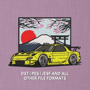 May include: Embroidered design featuring a yellow sports car with a black spoiler. The background includes a red sun, a mountain, and cherry blossoms. Text at the bottom reads: DST | PES | JESF AND ALL OTHER FILE FORMATS.