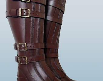May include: A pair of tall, brown leather boots with multiple straps and gold-colored buckles. The boots have a classic design with a rounded toe and a low heel. The leather appears to be smooth and polished, giving the boots a sophisticated look.