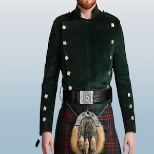 Puede incluir: Una chaqueta verde oscuro con botones plateados y un cinturón negro con hebilla plateada. La chaqueta se lleva sobre una falda escocesa a cuadros.