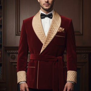 May include: A burgundy velvet smoking jacket with a quilted champagne-colored shawl collar, cuffs, and pocket trim. The jacket features a matching belt and a black bow tie. The lining is a light champagne color.