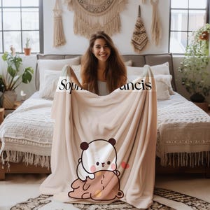 May include: A soft, beige fleece blanket with a cute cartoon panda and bear design. The blanket has the names "Sophia" and "Francis" printed on it.