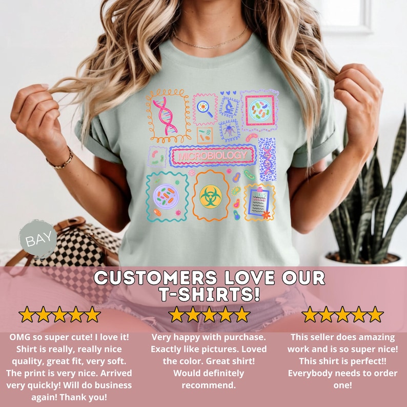 May include: A light green t-shirt featuring a colorful microbiology design. The design includes various scientific illustrations and the word "MICROBIOLOGY". The shirt also has the text "CUSTOMERS LOVE OUR T-SHIRTS!"