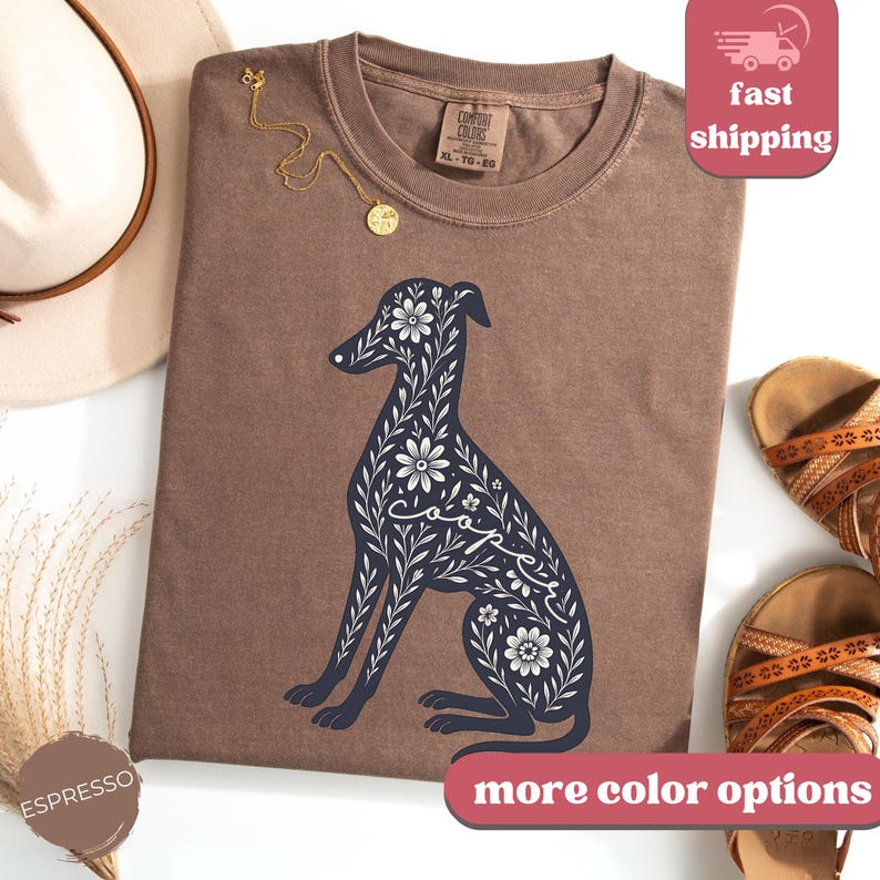 May include: Brown t-shirt with a floral design of a dog. The dog is outlined in black and the flowers are white. The word "Cooper" is written in the design.