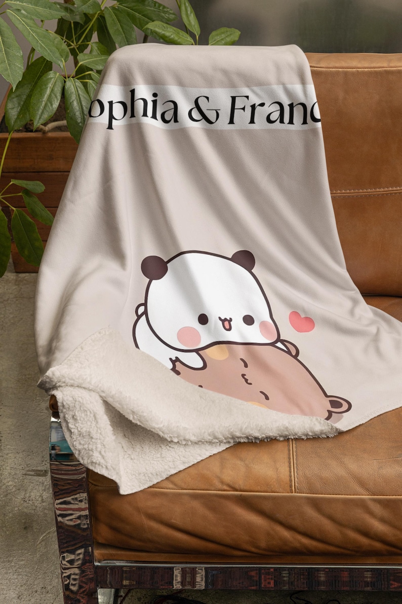 May include: A beige fleece blanket with a panda and bear illustration. The blanket has the text "Sophia & Franc" printed on it.