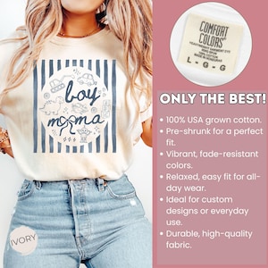 May include: Ivory-colored t-shirt with a blue and white design featuring the words "boy momma" and illustrations of toys. The shirt is made of 100% USA grown cotton.