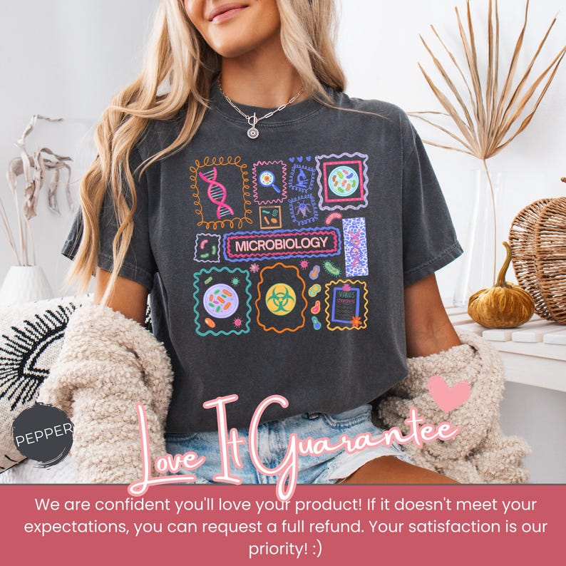 May include: Dark gray t-shirt featuring a colorful microbiology design with various scientific illustrations and the word "MICROBIOLOGY". The shirt has a vintage, worn look.