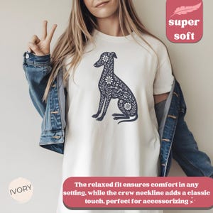 May include: White t-shirt with a navy blue floral design of a dog. The text "super soft" is in a pink box in the upper right corner of the image. The text "IVORY" is in a pink circle in the lower left corner of the image.