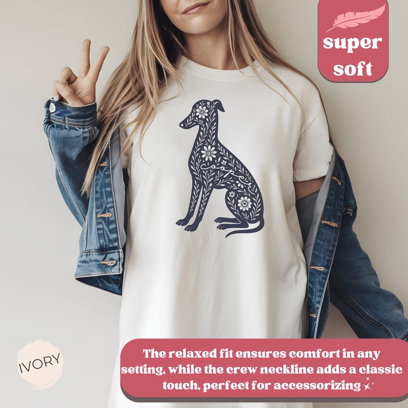 May include: White t-shirt with a navy blue floral design of a dog. The text "super soft" is in a pink box in the upper right corner of the image. The text "IVORY" is in a pink circle in the lower left corner of the image.