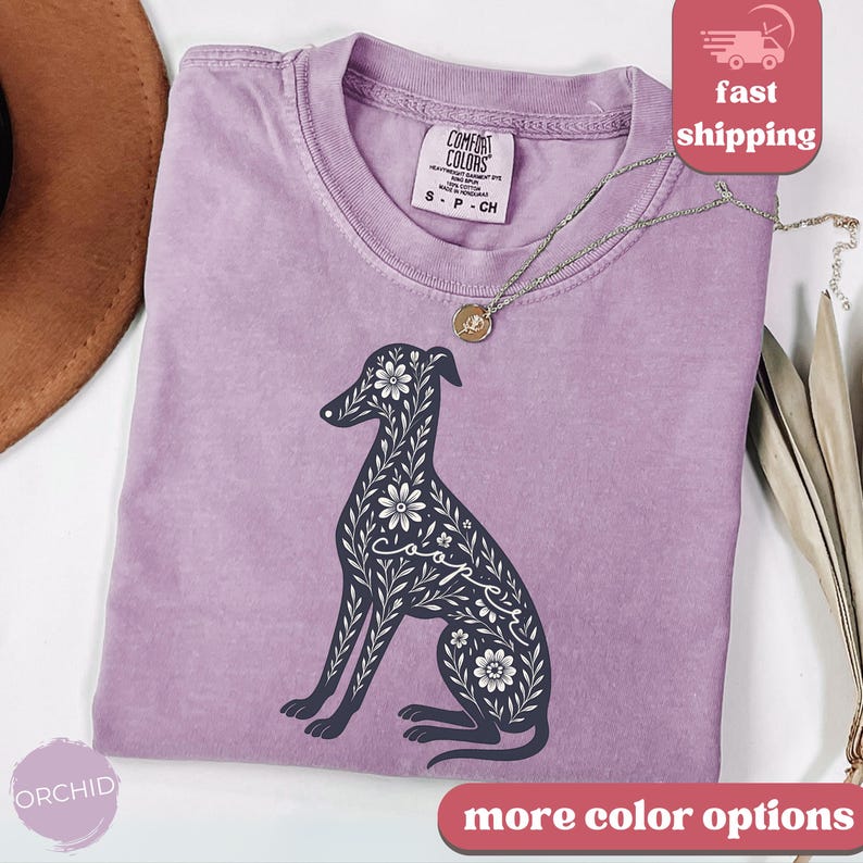 May include: Purple t-shirt with a floral design of a greyhound dog. The design includes the word "coffe" in the dog's body.