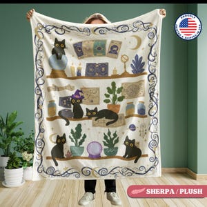 May include: A cream-colored throw blanket featuring a whimsical design of black cats, tarot cards, and mystical elements. The blanket has a shelf-like pattern with various objects and a decorative border. The words "SHERPA / PLUSH" are printed on the bottom right.