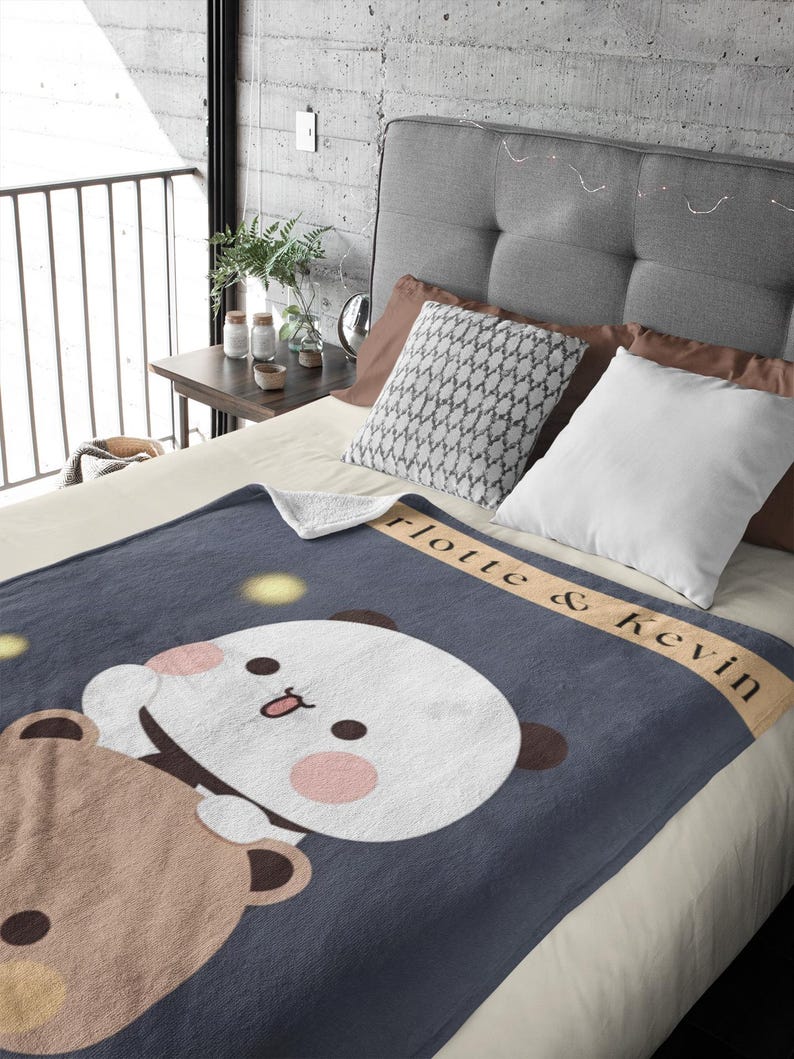 Pu&ograve; includere: Una morbida coperta in pile blu con un orso marrone e un panda bianco che si abbracciano. La coperta ha il testo "Lotte & Kevin" su uno stendardo beige.