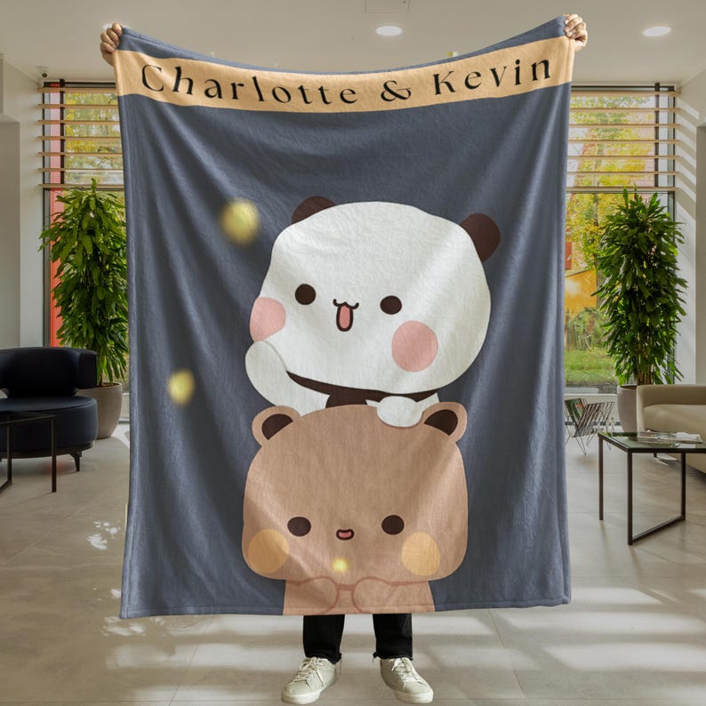 Pu&ograve; includere: Una coperta in pile blu con un orso marrone e un panda bianco sopra. La coperta ha il testo "Charlotte & Kevin" su di essa.