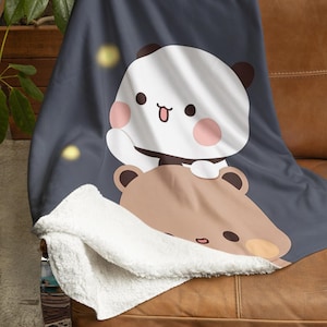 Pu&ograve; includere: Una morbida e soffice coperta con uno sfondo blu scuro che presenta un panda bianco con guance rosa e un orso marrone con un naso marrone chiaro. La coperta &egrave; foderata in sherpa bianco e ha una striscia marrone con il testo "Charlotte & Kev".